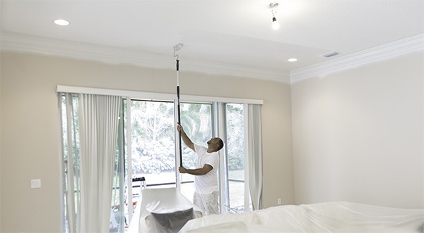 Painter using a roller to paint the ceiling
