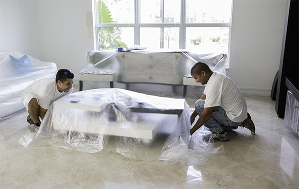 Painters covering furniture in preparation for painting interior walls